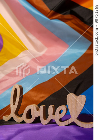 Wooden word love with heart romance on Rainbow LGBTQIA flag made from silk material. Valentine's Day greeting card. Symbol of LGBTQ pride month. Equal rights. Peace and freedom. Support LGBTQIA Wooden word love with heart romance on Rainbow LGBTQIA flag made from silk material. Valentine's Day greeting card. Symbol of LGBTQ pride month. Equal rights. Peace and freedom. Support LGBTQIA 99751268