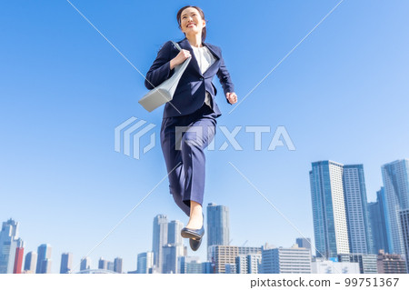 Career woman running in a suit in the city 99751367