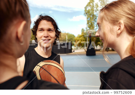 A group of young men and women have fun in the city playground with a ball, laugh and chat, have fun 99752609