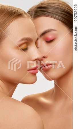 Love. Couple of beautiful sensual young women, blond and brunette with well-kept skin posing over light background. Concept of natural beauty, fashion, skin care and health 99752996