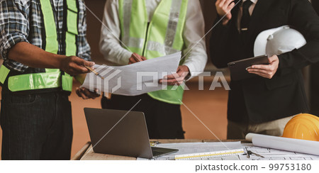 Architect team working with blueprints for architectural plan, engineer sketching a construction project, green energy concept Architect team working with blueprints for architectural plan, engineer sketching a construction project, green energy concept 99753180
