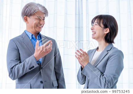 A middle male boss and a young female subordinate who talk while standing A middle male boss and a young female subordinate who talk while standing 99753245