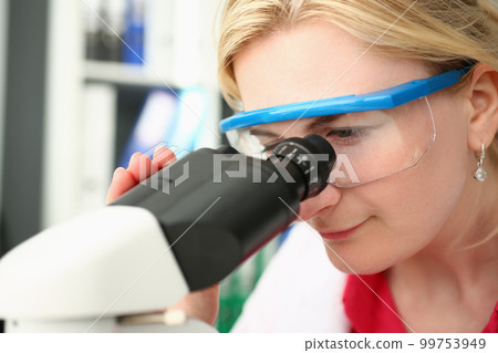 Portrait of focused female scientist looking through microscope in laboratory Portrait of focused female scientist looking through microscope in laboratory 99753949