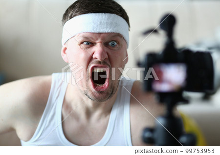 Emotionally angry sports blogger man screaming at camera Emotionally angry sports blogger man screaming at camera 99753953