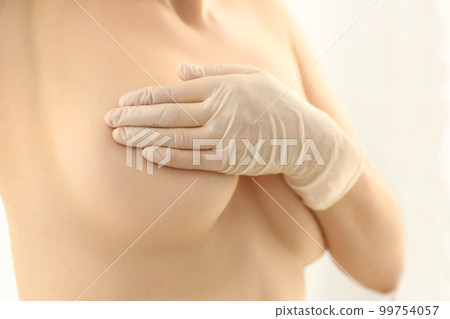 Woman hand in rubber gloves and naked female breast 99754057