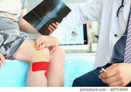 X-ray image of knee injury patient with kinesio tape on knee at orthopedist appointment X-ray image of knee injury patient with kinesio tape on knee at orthopedist appointment 99754094