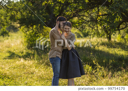 man telling his girlfriend's secret in his ear man telling his girlfriend's secret in his ear 99754170