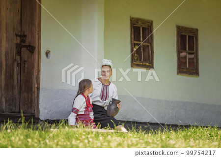 mother and daughter sitting near the house 99754217