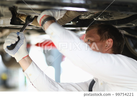 Auto mechanic checks running gear of car at service station 99754221