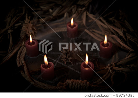 Occultist dripping hot wax on voodoo doll, magic rituals, black spell, horror. 99754385