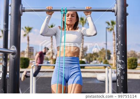 Woman doing pull-up. Strong girl in sportswear doing pull up exercise. Be H3althy. Woman doing pull-up. Strong girl in sportswear doing pull up exercise. Be H3althy. 99755114