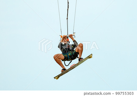 Young kitesurfer jumping in the sky on the board Young kitesurfer jumping in the sky on the board 99755303