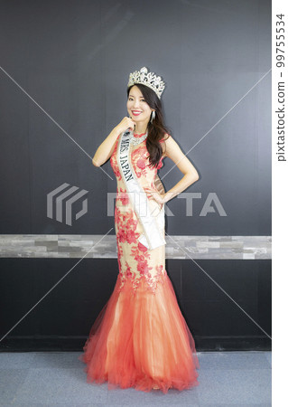 A tall beautiful woman wearing a cherry-colored dress A tall beautiful woman wearing a cherry-colored dress 99755534