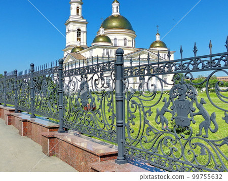 Forged fence around the Nevyansk leaning tower. On the fence is the coat of arms of the Demidov family. In the background is the Transfiguration Cathedral. Nevyansk, Russia 99755632
