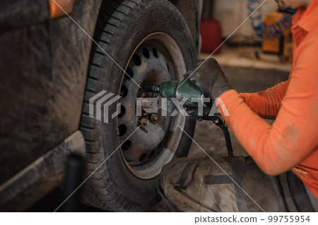 Replacement and repair of wheels and shock absorbers on a car in a garage 99755954