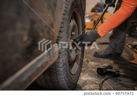 Replacement and repair of wheels and shock absorbers on a car in a garage 99755972