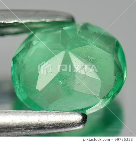 Natural gemstone green emerald on gray background 99756338