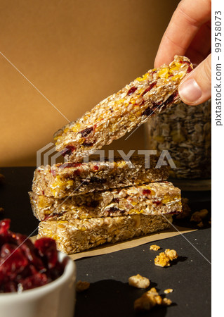 Woman takes Homemade Granola energy bar. Variety of protein granola breakfast bars, with nuts, raisins dried cherries and chocolate. Healthy nutrition eating Gluten free cereal dieting snack super Woman takes Homemade Granola energy bar. Variety of protein granola breakfast bars, with nuts, raisins dried cherries and chocolate. Healthy nutrition eating Gluten free cereal dieting snack super 99758073