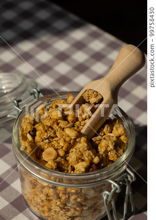 Homemade granola with nuts and seeds in eco glass jar. Healthy snack on breakfast. Muesli from oatmeal, raisins, honey, cranberry, flax, almond, cashew, freshly baked Homemade granola with nuts and seeds in eco glass jar. Healthy snack on breakfast. Muesli from oatmeal, raisins, honey, cranberry, flax, almond, cashew, freshly baked 99758430