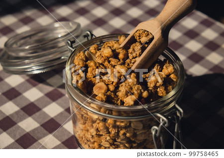 Homemade granola with nuts and seeds in eco glass jar. Healthy snack on breakfast. Muesli from oatmeal, raisins, honey, cranberry, flax, almond, cashew, freshly baked Homemade granola with nuts and seeds in eco glass jar. Healthy snack on breakfast. Muesli from oatmeal, raisins, honey, cranberry, flax, almond, cashew, freshly baked 99758465