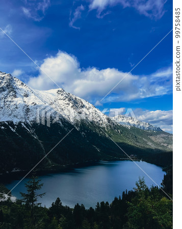 Morskie Oko lake Snowy Mountain Hut in Polish Tatry mountains, Zakopane, Poland. Beautiful green hills and mountains in dark clouds and reflection on the lake Morskie Oko lake 99758485