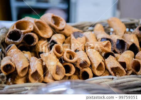 Sweet empty fried cannoli in basket on counter at food market 99759351
