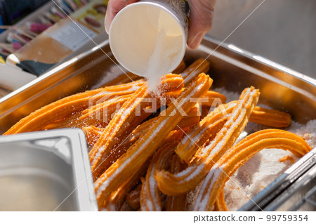 Chef preparing homemade crunchy churros at street food market: close up Chef preparing homemade crunchy churros at street food market: close up 99759354