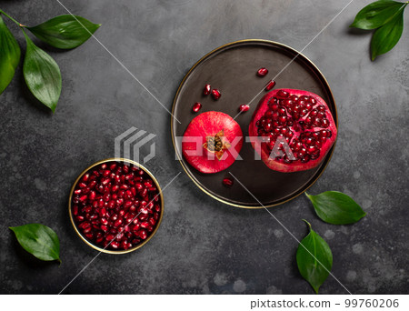 ripe pomegranate on a plate and peeled pomegranate grain. 99760206
