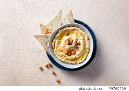 Hummus, chickpea dip in ceramic bowl over beige textured background. 99760209