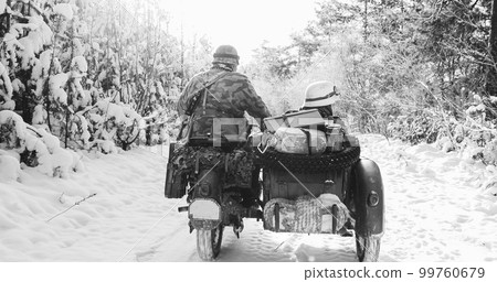 Re-enactors Dressed As World War II German Wehrmacht Infantry Soldiers Driving Old Tricar, Three-wheeled Motorcycle in Winter Snowy Forest 99760679