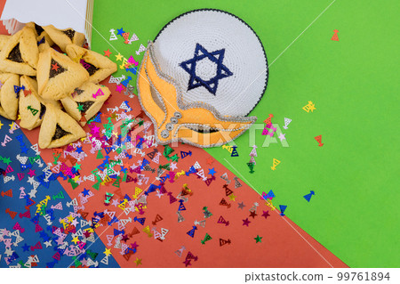 During Purim festival, Jews celebrate this religious holiday with cookies, tallit, noisemaker masks, and hamantaschen celebration symbols that remind them of holiday 99761894