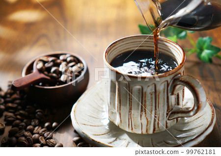 Coffee being poured in the sunlight filtering through the trees 99762181