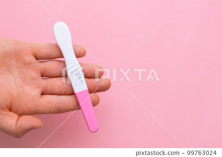 Man hand holding a pregnancy test on the pink background with copy space 99763024