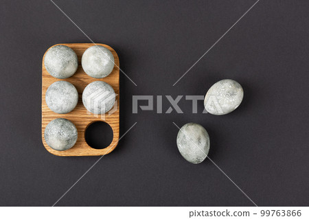 Grey Easter eggs in a wooden stand on a black background. Minimal Easter concept 99763866