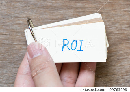 Hand hold flash card with handwriting in word ROI (Abbreviation of Return on Investment) on wood background 99763998