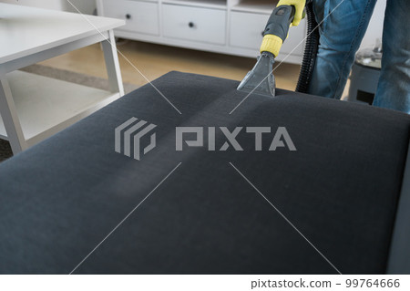 Man in protective rubber glove cleaning sofa with professionally extraction method with washing vacuum cleaner. Early spring regular cleanup. Commercial cleaning company concept 99764666