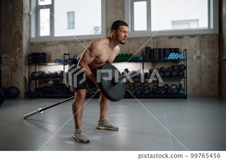 Strong man prepares to lift heavy weights training with barbell 99765456
