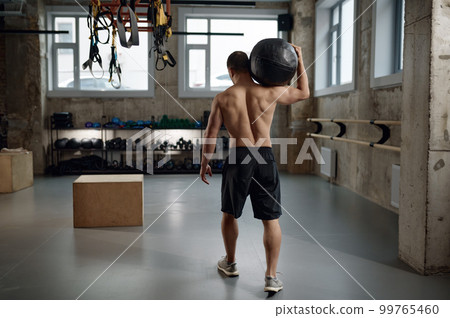 Portrait of male athlete holding med ball on shoulder after functional training 99765460