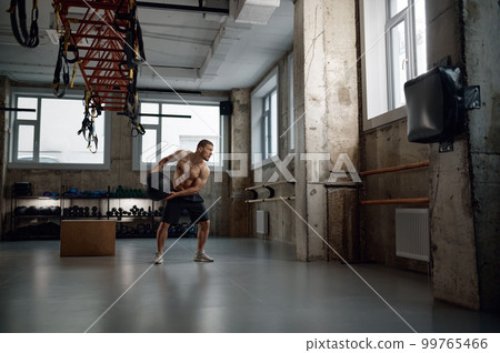 Full length portrait of young muscular man training with med ball in gym 99765466
