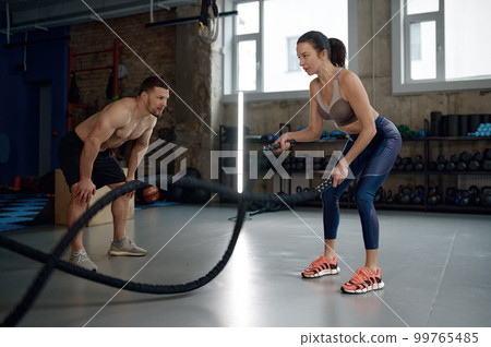 Personal fitness trainer supporting female client 99765485