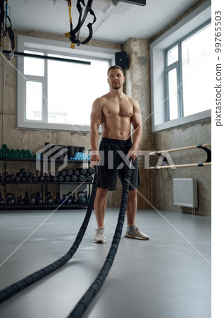Young strong man pulling training sports rope front view 99765503