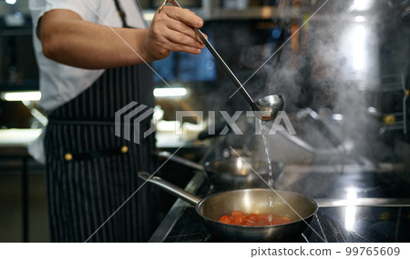 Chef adding white wine to frying pan with tomato sauce for pasta Chef adding white wine to frying pan with tomato sauce for pasta 99765609