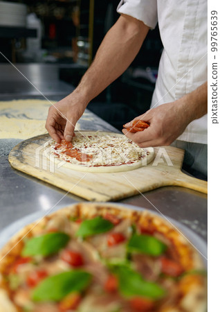 Above view on chef hand preparing pizza base on professional kitchen 99765639