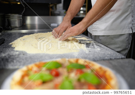 Closeup chef hands mixing flour for kneading pizza dough 99765651
