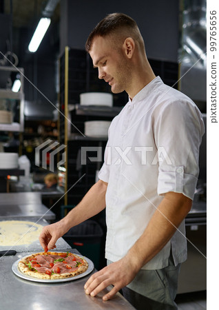 Pizzaiolo making pizza at kitchen with closeup focus on hand 99765656