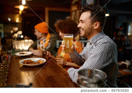 Happy smiling man sitting at sports bar counter desk looking at camera 99765680