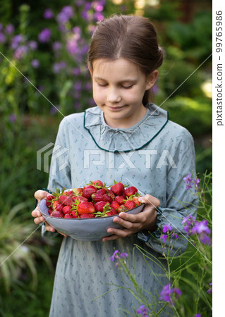 Cute little girl in a vintage dress with a bowl of ripe strawberries Cute little girl in a vintage dress with a bowl of ripe strawberries 99765986