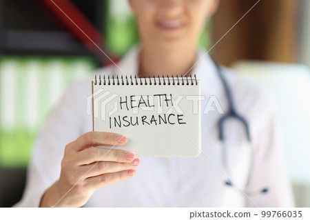 Female doctor showing notepad with words health insurance Female doctor showing notepad with words health insurance 99766035