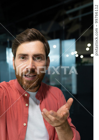 Close-up photo. Young businessman, freelancer, programmer conducts a video conference on a video call, holds a phone in his hands, talks to the camera, vertical photo. Close-up photo. Young businessman, freelancer, programmer conducts a video conference on a video call, holds a phone in his hands, talks to the camera, vertical photo. 99766112