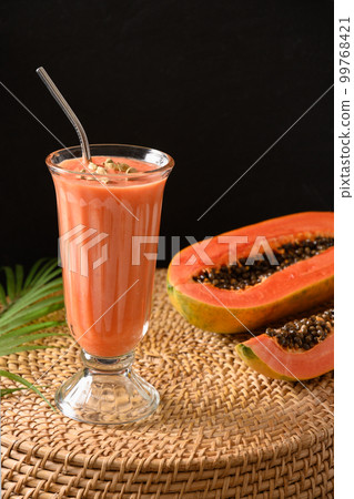 Papaya lassi in glass on black background. 99768421